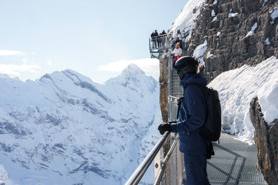 Rear view of man walking on snowcapped mountain