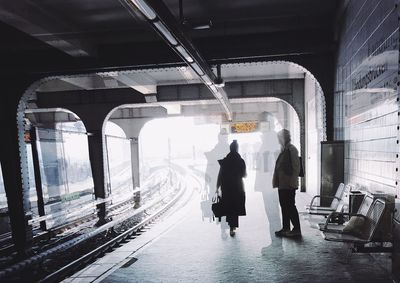 Rear view of people walking on railroad station