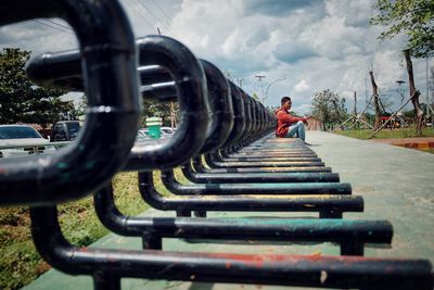 Side view of man sitting on bicycle rack