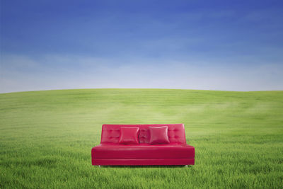 Couch on field against sky