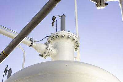 Low angle view of pipe connected to container against sky