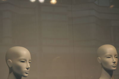 Close-up of mannequins against glass in shop