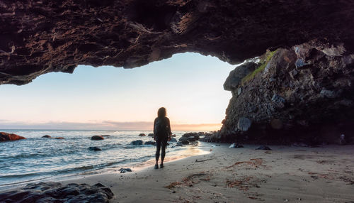 Rear view of people standing on rock at beach