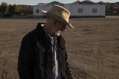 Adult man in cowboy hat standing in front of white building