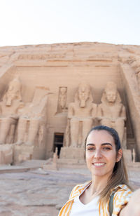 Portrait of young woman standing against wall