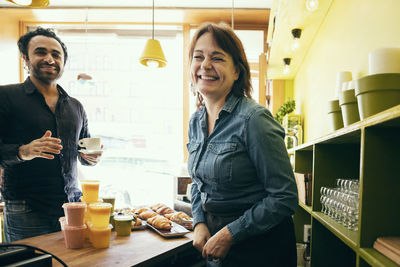 Happy female owner standing with customer in cafe