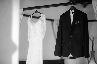 Wedding dress and suit hanging from rack