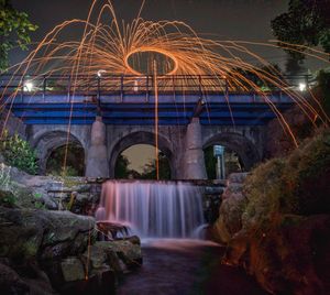 Illuminated arch bridge over river at night