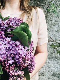 Close-up of woman with bouquet against plants