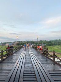 People on railway bridge against sky