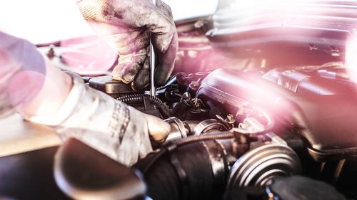 Close-up of mechanic hands repairing car engine in garage