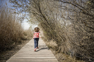 Rear view of girl running on boardwalk