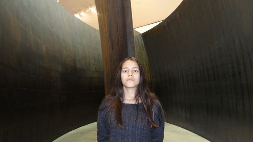 Portrait of teenage girl standing against column in building