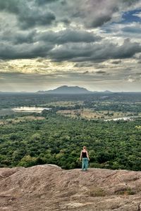 Rear view of woman standing on landscape against cloudy sky