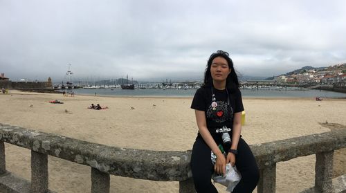 Portrait of young woman standing by sea against sky