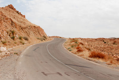 Road leading towards mountains against sky