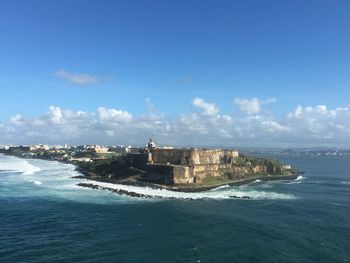 Buildings by sea against blue sky