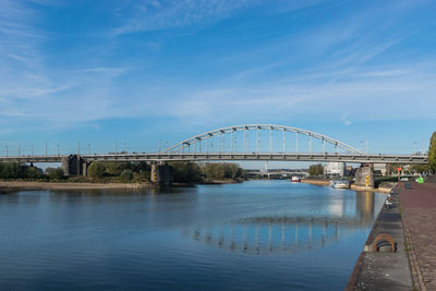Bridge over river and a cow against blue sky