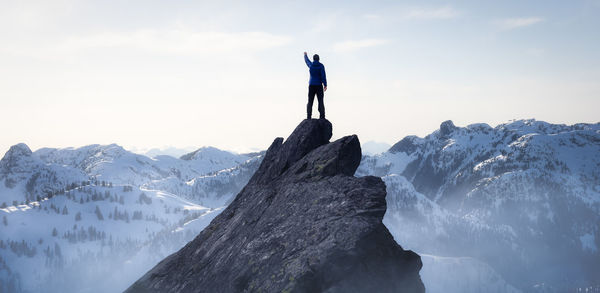 Rear view of person standing on rock against sky