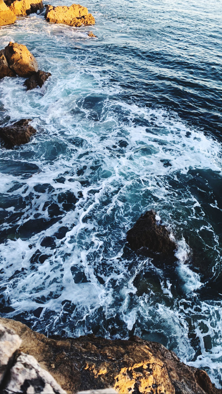 HIGH ANGLE VIEW OF ROCKS ON SEA