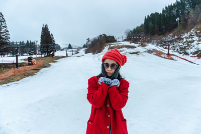 Portrait of woman standing on snow covered landscape during winter