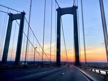 Bridge over road against sky during sunset