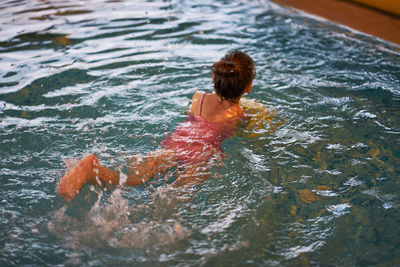 Rear view of boy swimming in water