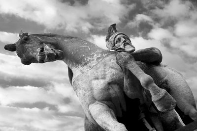 Low angle view of warrior and horse statue against cloudy sky