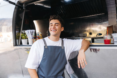 Portrait of young man standing in car