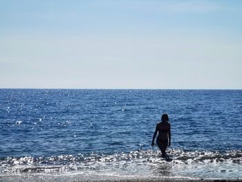 Rear view of man on sea against clear sky