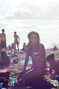 Woman sitting on beach against sky