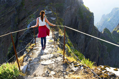 Rear view of woman walking on footbridge