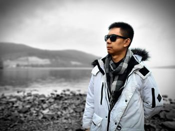 Portrait of young man standing against lake during sunset