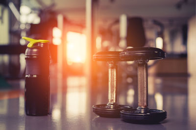 Close-up of water bottle and dumbbells on floor in gym