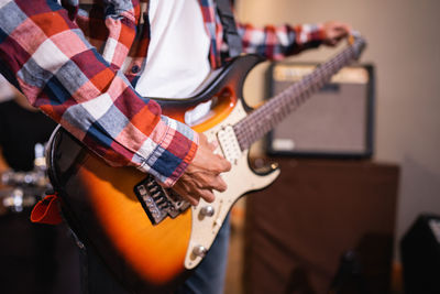 Midsection of man playing guitar