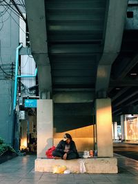 Beggar sitting under bridge