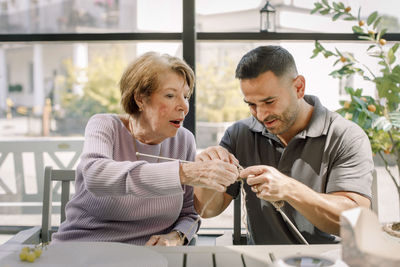 Senior woman and male nurse crocheting together at retirement home