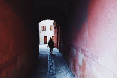 Rear view of woman walking in tunnel