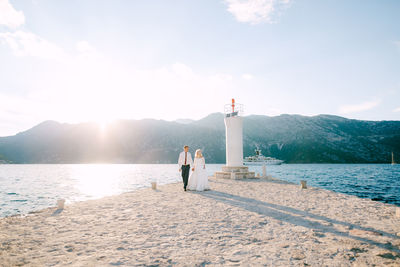 People on lighthouse by sea against sky