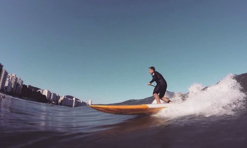 Friends on shore against clear sky