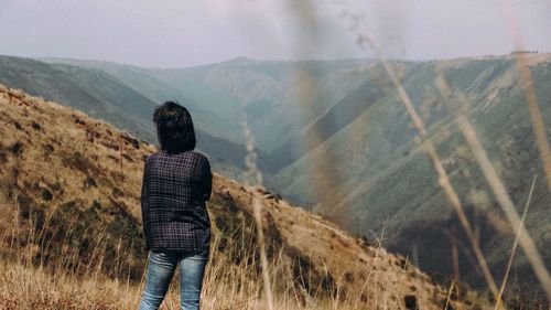 Rear view of woman looking at mountain against sky