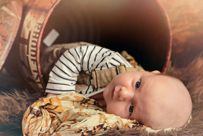 Portrait of cute boy lying in metal drum