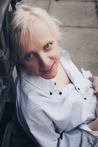 High angle portrait of smiling woman sitting on footpath