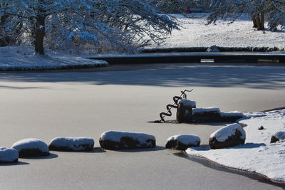 Snow covered rocks by lake during winter