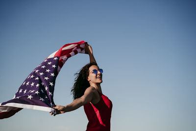 Woman holding umbrella against clear blue sky