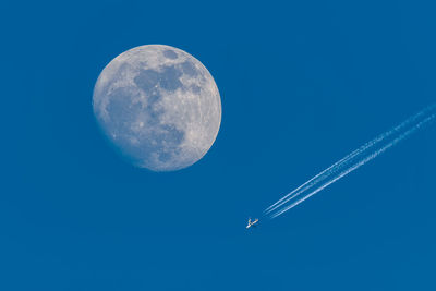 Full moon and flying plane with blue sky.