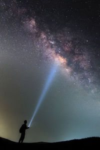 Silhouette man exploring star field at night