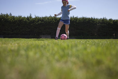 Girl practicing soccer on grassy field