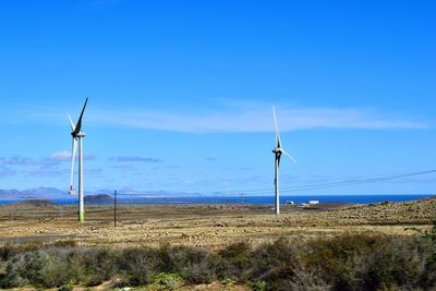 Wind turbines on field against sky