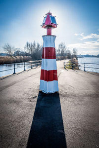 Red umbrella by lake against sky